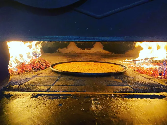 La socca de Chez Thérésa qui cuit dans le four à bois, flammes vives